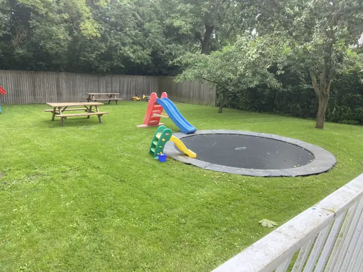 Familiehave med græsplæne, trampolin og rutsjebane
